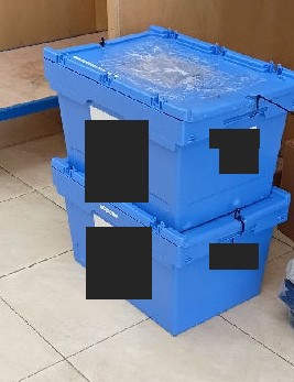 Two blue cases stacked at the delivery point, with labels redacted